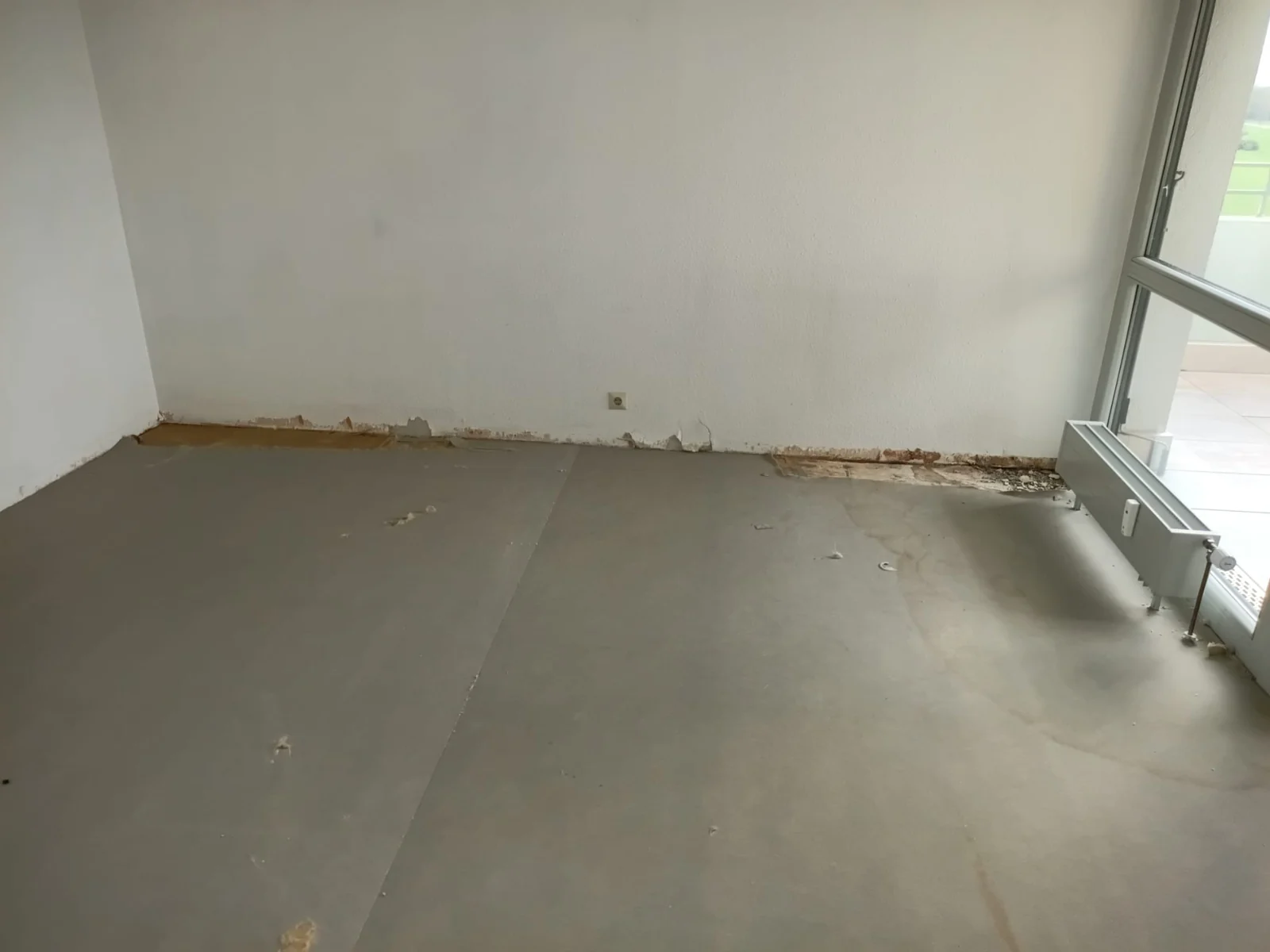 Raum mit freigelegtem Boden und Zugang zum Balkon